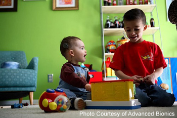 two boys playing with toys, one has a cochlear implant | photo courtesy of Advanced Bionics